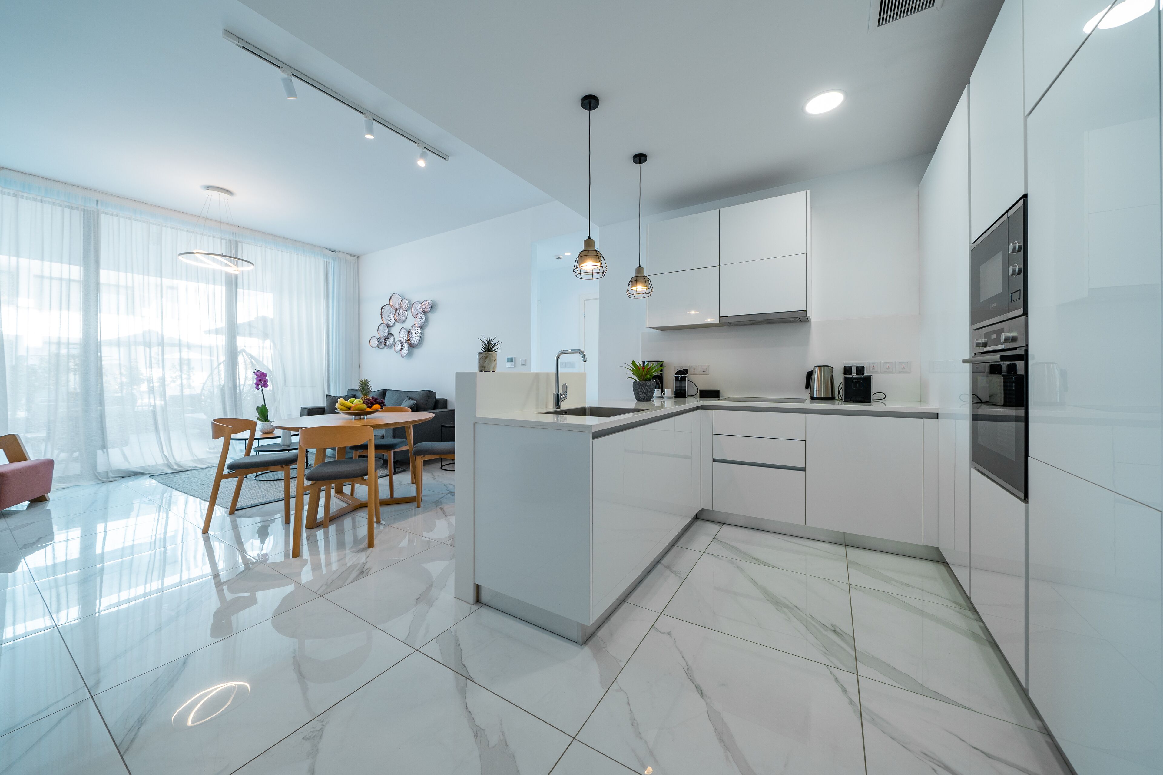A modern kitchen with white cabinetry, a marble countertop, and a central island.