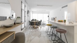 Une cuisine moderne dotée d’un îlot central, de tabourets de bar et d’un coin repas avec une table ronde et des chaises.