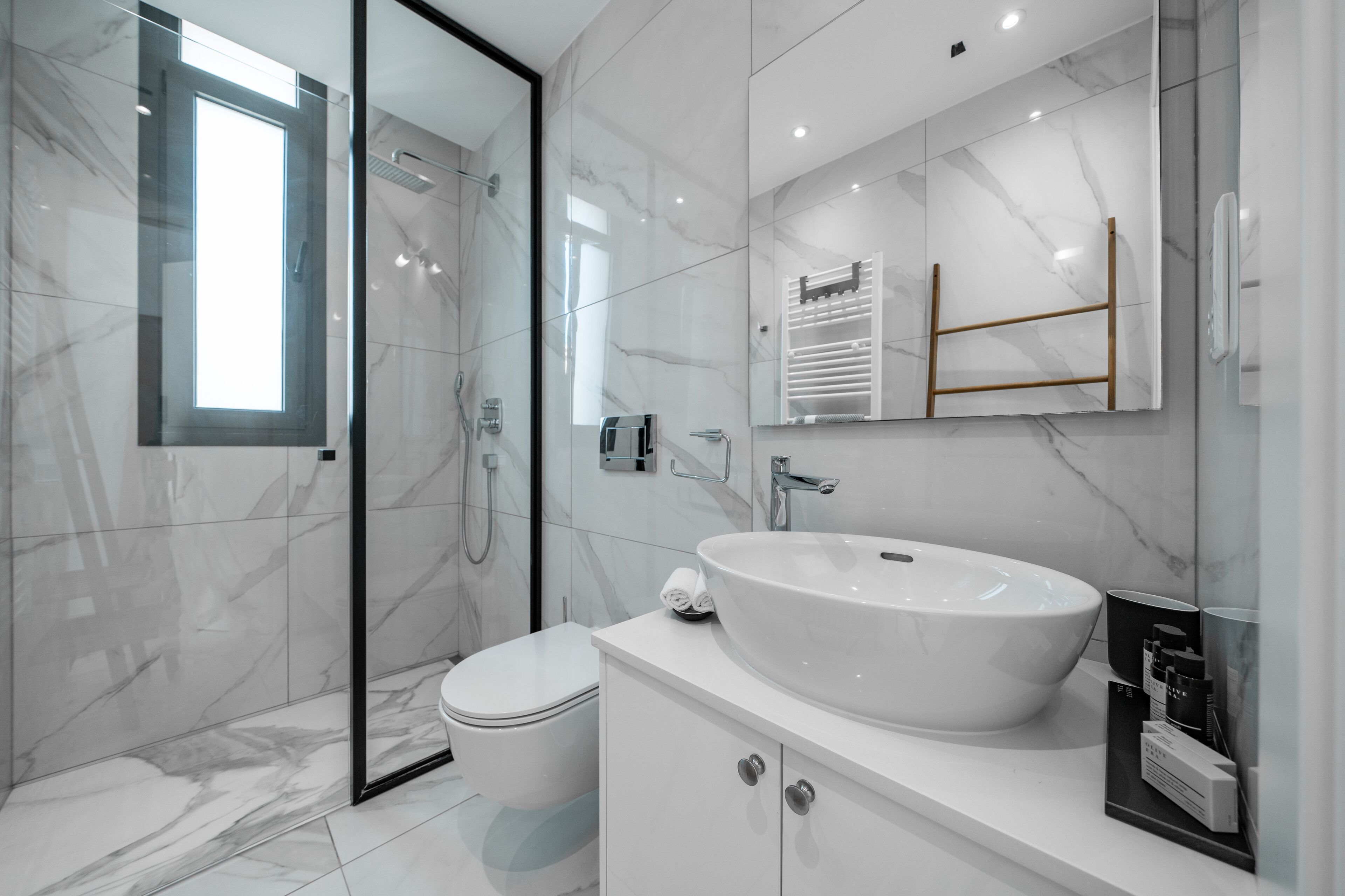 A modern bathroom with a glass shower enclosure, a white sink, and a toilet.