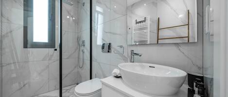 A modern bathroom with a glass shower enclosure, a white sink, and a toilet.