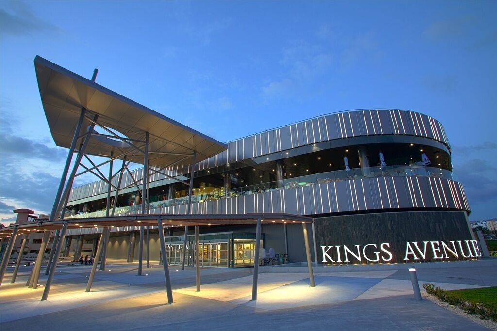 A modern building with a curved facade and a sign reading "KINGS AVENUE".