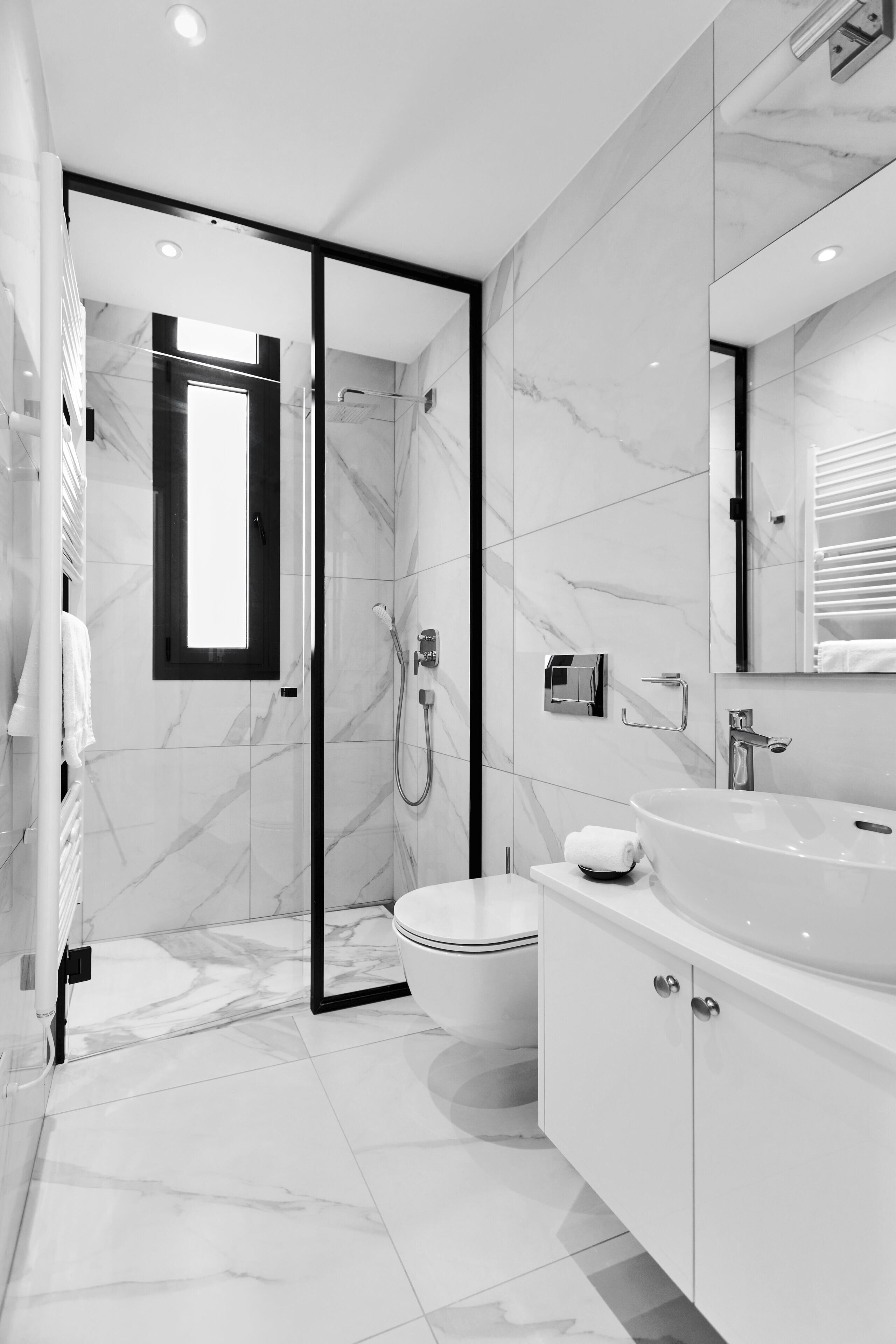 A modern bathroom with a glass-enclosed shower, a toilet, and a vanity with a sink.