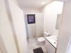 A modern bathroom with a glass shower enclosure, a toilet, and a sink. - The White Pearl Apartment (Larnaca)