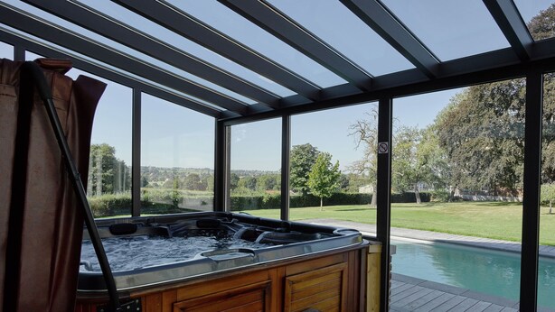 A hot tub in a glass-enclosed room with a view of a swimming pool and a landscaped garden. - Lavish Castle in Thimister with Turkish Steambath, Sauna (Thimister-Clermont)