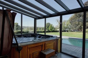 A hot tub in a glass-enclosed room with a view of a swimming pool and a landscaped garden. - Lavish Castle in Thimister with Turkish Steambath, Sauna (Thimister-Clermont)