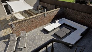 A rooftop patio with a brick wall, a white canopy, a barbecue grill, and a white sofa. - Lavish Castle in Thimister with Turkish Steambath, Sauna (Thimister-Clermont)