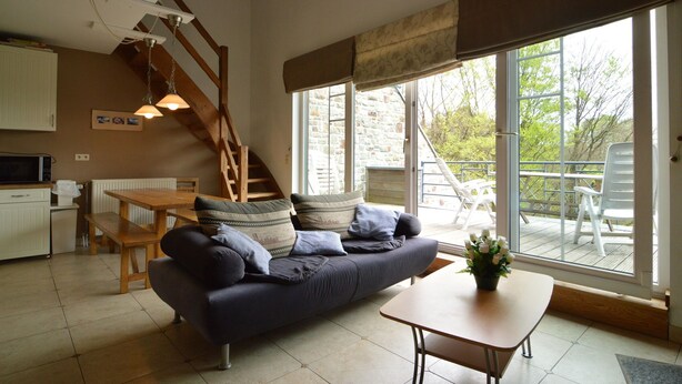 A cozy living room with a sofa, a dining table, and a staircase leading to an upper level.