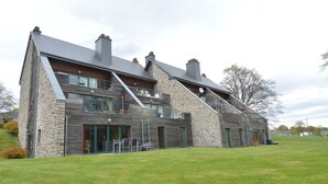 A modern two-story building with stone and wood exterior, large windows, and a spacious outdoor area.