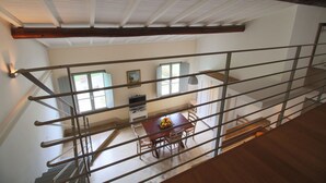 A dining area with a wooden table and chairs, a window with a view, and a staircase leading to another level. - Farmhouse in San Gimignano with Pool (San Gimignano)