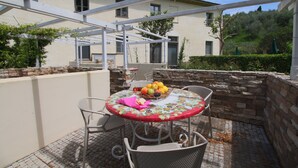 An outdoor patio with a round table, chairs, and a fruit basket. - Farmhouse in San Gimignano with Pool (San Gimignano)