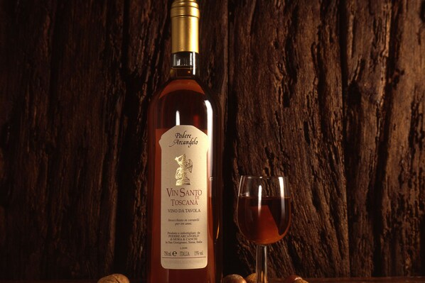 A bottle of wine with a label and a glass of wine against a wooden background.
