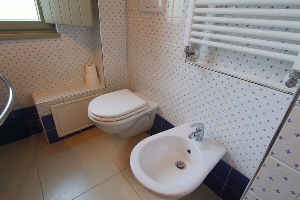 A bathroom with a toilet, bidet, and a sink.