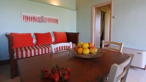 A dining area with a wooden table, red and white striped sofa, and a basket of fruit. - Farmhouse in San Gimignano near Piazza Cisterna (San Gimignano)