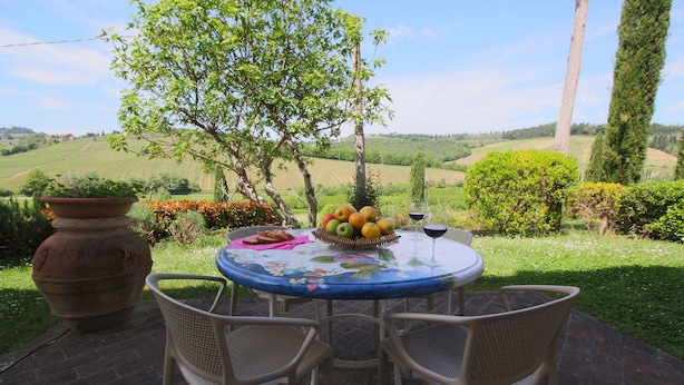 An outdoor table with wicker chairs, a fruit basket, a wine glass, and a potted plant. - Farmhouse in San Gimignano near Piazza Cisterna (San Gimignano)
