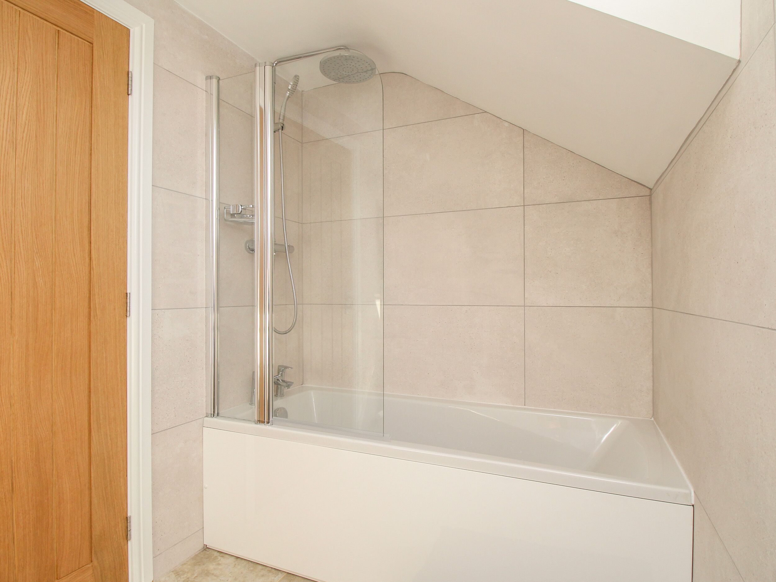 Un baño moderno con ducha envuelta en vidrio, una bañera blanca y una puerta de madera.