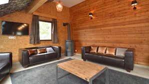 Una sala de estar acogedora con dos sofás de cuero, una mesa de centro de madera, una chimenea y un televisor montado en la pared.
