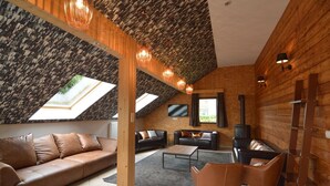 Una sala de estar acogedora con techos altos, paredes de madera, una chimenea y un ventanal grande.
