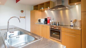 A modern kitchen with stainless steel appliances, wooden cabinets, and a built-in oven.
