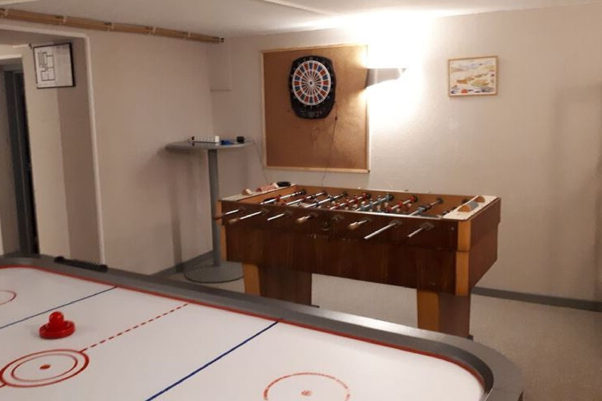 An indoor recreational area with a foosball table, a dartboard, and an ice hockey rink.