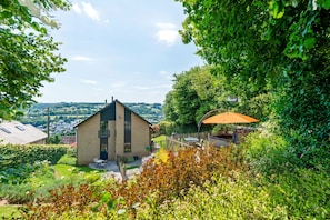 A modern house with a brick exterior, a small patio, and a view of a town in the background.