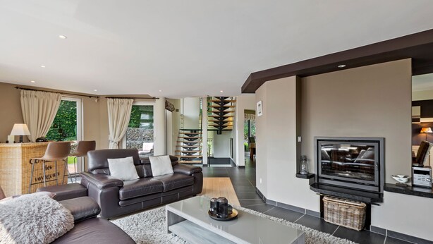 A modern living room with a leather sofa, a flat-screen TV, and a fireplace. - Holiday Home in Malmedy with Sauna & Bubble Bath (Malmedy)