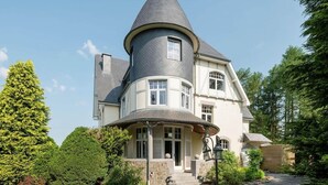 A large, two-story house with a distinctive turret and a wrap-around porch.