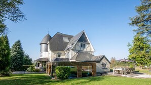 A large, two-story house with a prominent turret and a covered patio area.