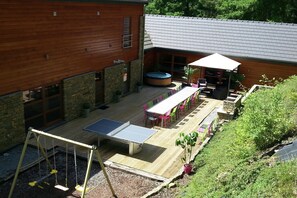 A wooden house with a patio area featuring a ping pong table, outdoor seating, and a hot tub. - Holiday Home in Stoumont with Private Sauna (Stoumont)