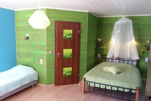 Een kamer met twee enkele bedden, een houten deur met decoratieve panelen, een hemelbed en een hanglamp.