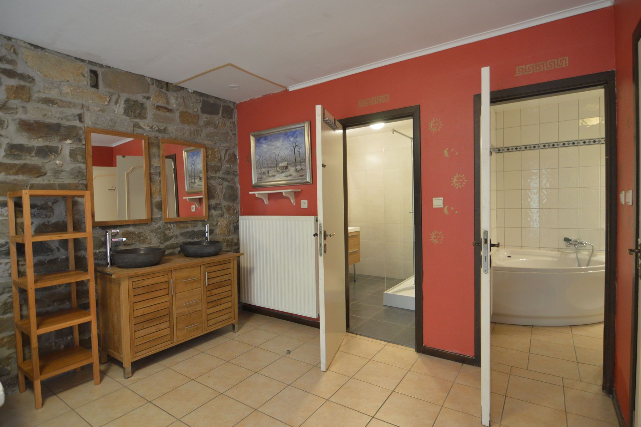 A bathroom with a stone wall, a wooden vanity, a bathtub, and a shower.