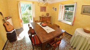 Un espace repas comprenant une table en bois, des chaises, un lustre et une vue par la fenêtre.