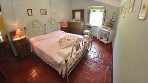 Une chambre à coucher comprenant un lit, une commode, une coiffeuse et une fenêtre donnant sur un paysage agréable.