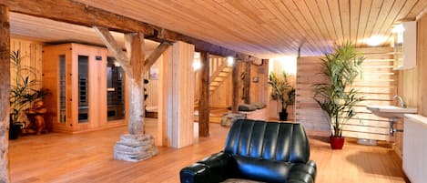 A wooden interior with a black leather sofa, wooden beams, and potted plants.