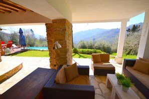 Uma área de pátio ao ar livre com piso de pedra, móveis de vime e vista para montanhas.