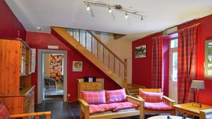 Ein gemütliches Zimmer mit einer Holztreppe, einer Sofagarnitur, einem kleinen Tisch und einer Lampe.