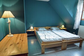 Une chambre avec un lit en bois, deux tables de chevet avec des lampes et une fenêtre avec des rideaux.