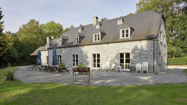 A stone building with a gravel driveway, outdoor seating, and a picnic table.