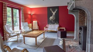A cozy living room with a fireplace, red walls, and a large deer painting.
