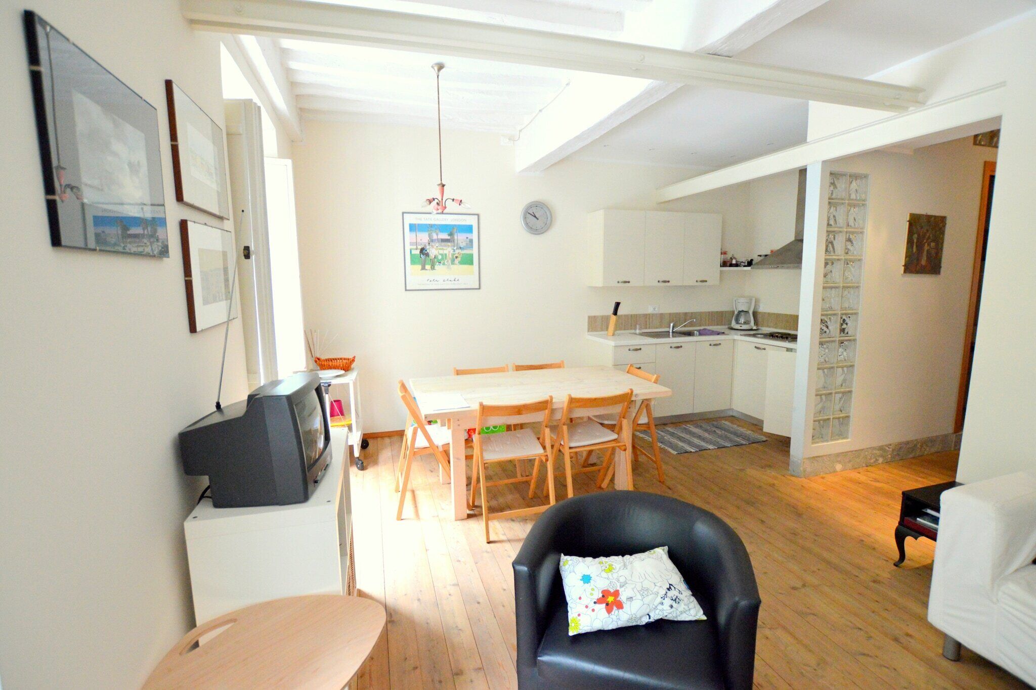 A compact living space with a dining area, a kitchen, and a seating area with a television.