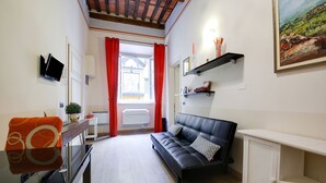 Ein modernes Wohnzimmer mit einer schwarzen Ledersofa, einer weißen Kommode und einem an der Wand befestigten Fernseher.