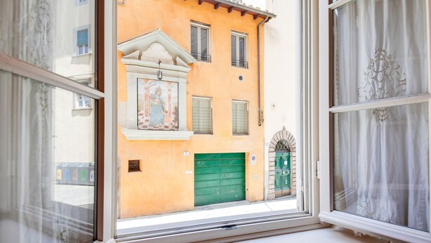 Ein Fenster mit Blick auf ein Gebäude mit einer grünen Tür und einem Wandgemälde.
