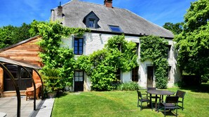 A house with a sloped roof, a covered patio, and a well-maintained lawn. - Magnificent Holiday Home in Baronville with Heated Pool & Billiards (Beauraing Ardennes)