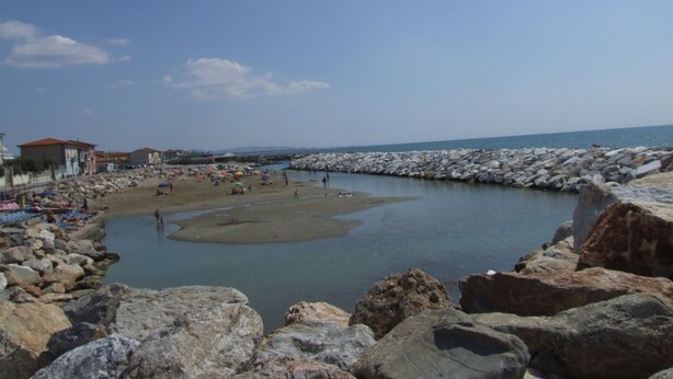 A coastal area with rocky shores, a sandy beach, and a calm water body. - Pisa Stay close to Leaning Tower (Pisa)