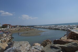 Una zona costera con costas rocosas, una playa de arena y una masa de agua tranquila.