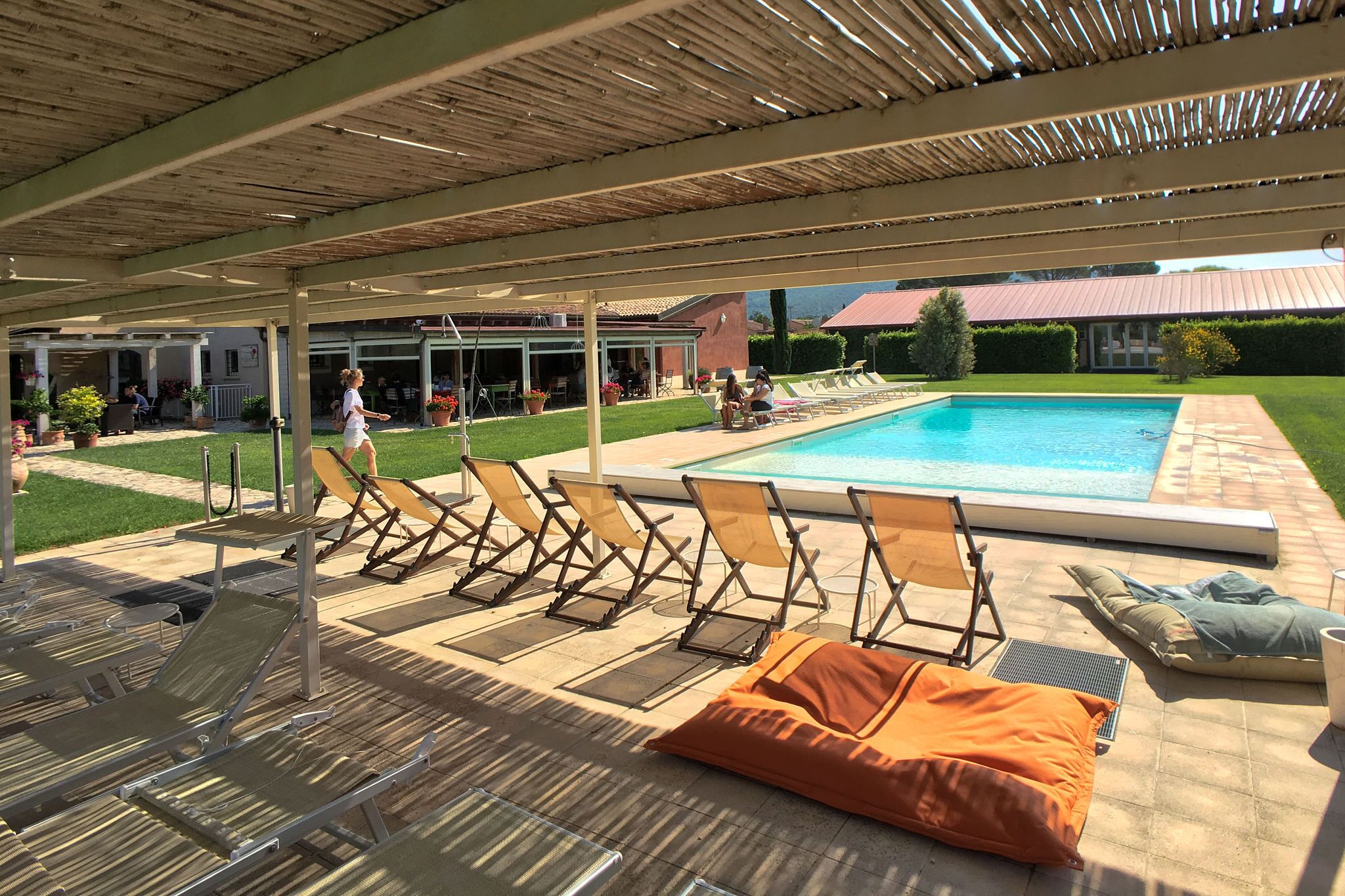 A covered pool area with lounge chairs and a swimming pool.