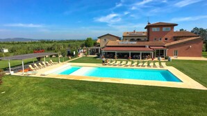 A large house with a swimming pool, a covered patio, and a well-maintained lawn.