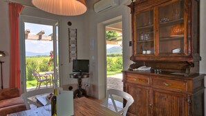 Un comedor con una mesa de madera, sillas, un televisor y un mueble con puertas de vidrio.