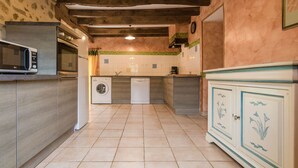 A kitchen with a washing machine, microwave, oven, and a cabinet with floral designs. - Cosy holiday home in Marsac with pool (Marsac)