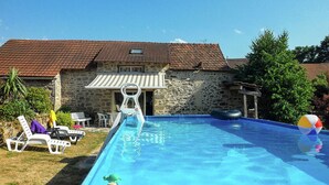 A swimming pool with lounge chairs and a stone building with a tiled roof. - Cosy holiday home in Marsac with pool (Marsac)