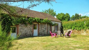 A stone building with a tiled roof, a small porch with chairs, and a grassy yard. - Cosy holiday home in Marsac with pool (Marsac)